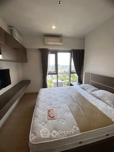 Modern bedroom with city view, featuring a large bed and wall-mounted TV, perfect for urban living.