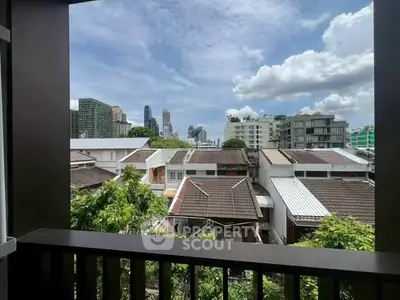 Stunning cityscape view from a balcony overlooking urban rooftops and skyline.