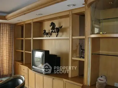 Spacious living room with built-in wooden shelves and vintage TV, perfect for cozy family gatherings.