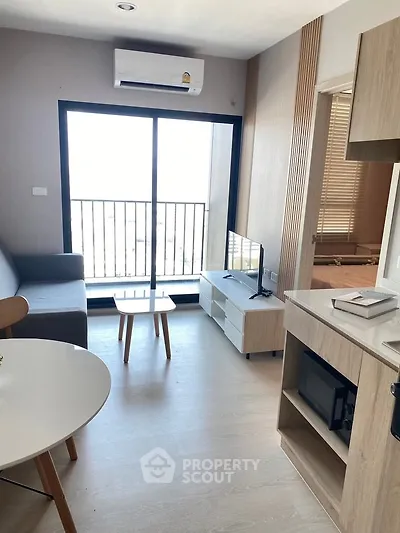 Modern living room with balcony view, sleek furniture, and natural light in a stylish apartment.