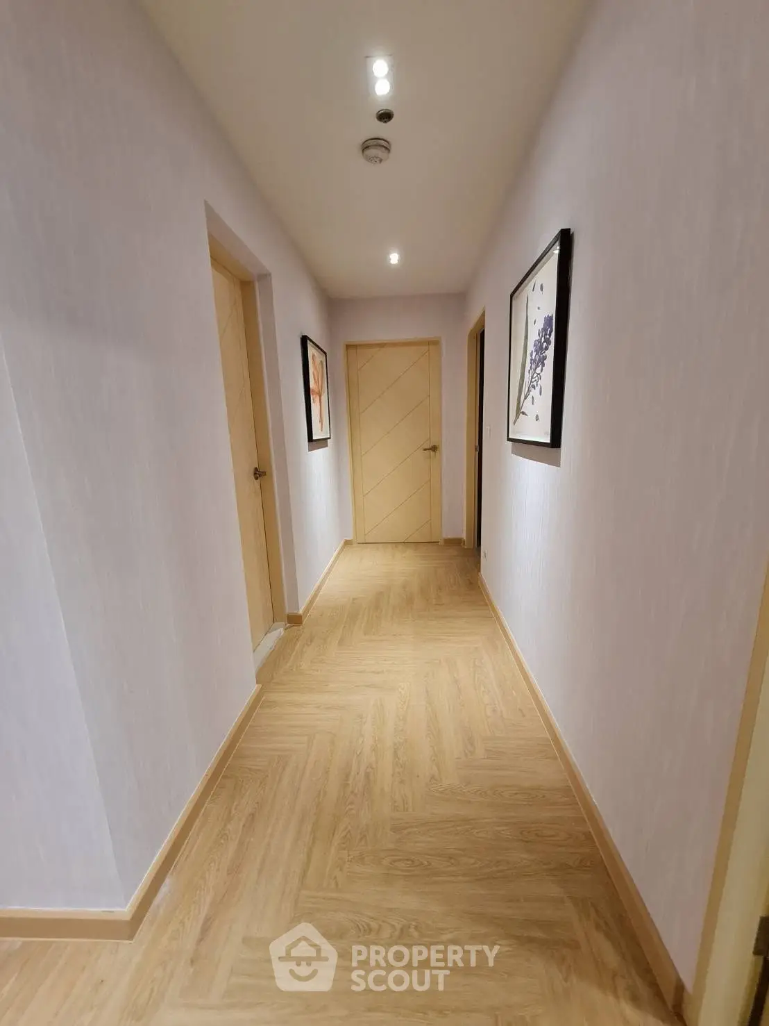 Elegant hallway with wooden flooring and modern artwork in a residential building.