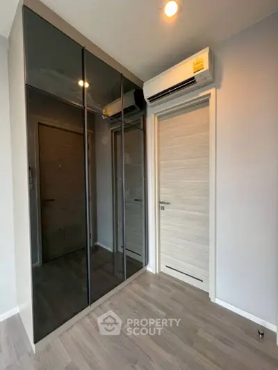 Modern bedroom with sleek mirrored wardrobe and air conditioning unit