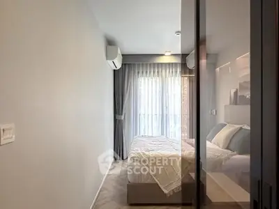Modern bedroom with large window and elegant curtains, featuring a cozy bed and air conditioning.
