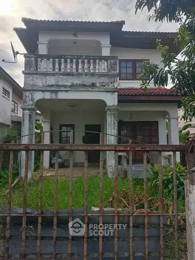 Charming two-story house with balcony and lush garden, perfect for family living.