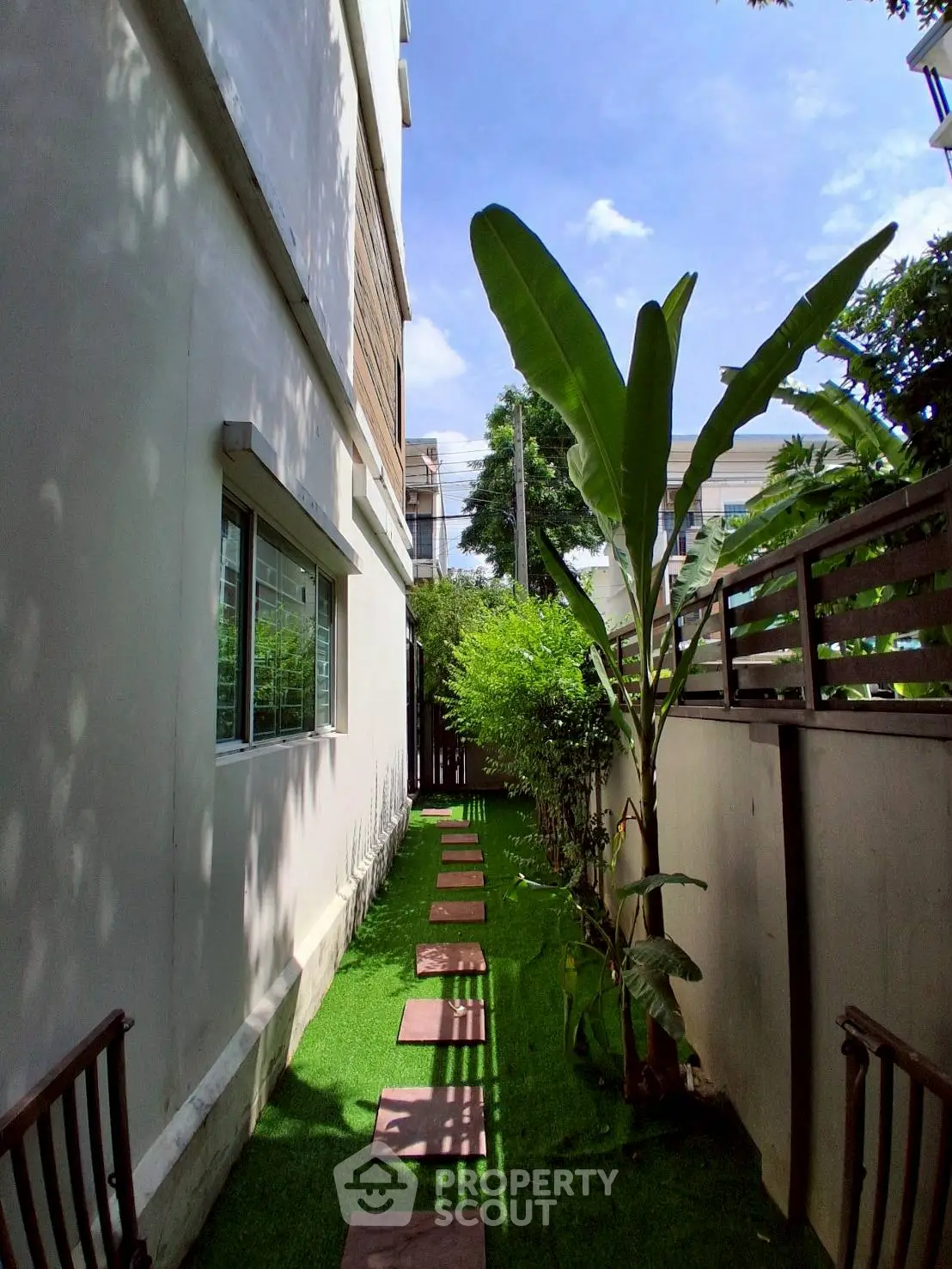 Charming narrow garden path with lush greenery and modern exterior design, perfect for urban relaxation.