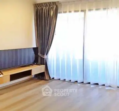 Spacious living room with large windows and elegant curtains in modern apartment.