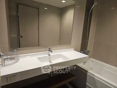 Modern bathroom with sleek design featuring a large mirror and bathtub, perfect for relaxation.
