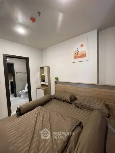 Cozy bedroom with modern decor and ensuite bathroom in stylish apartment.