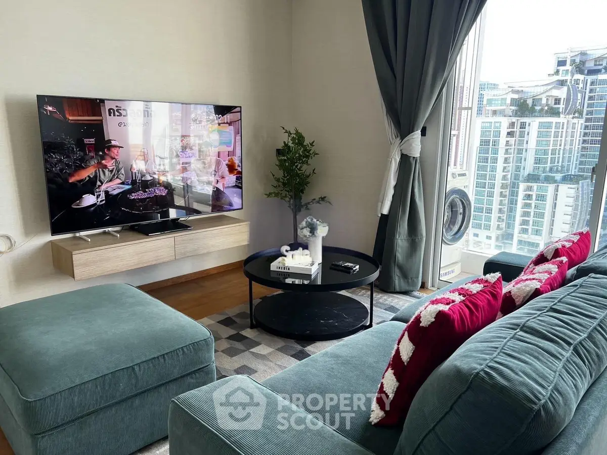 Modern living room with stylish decor, large TV, and city view from window.