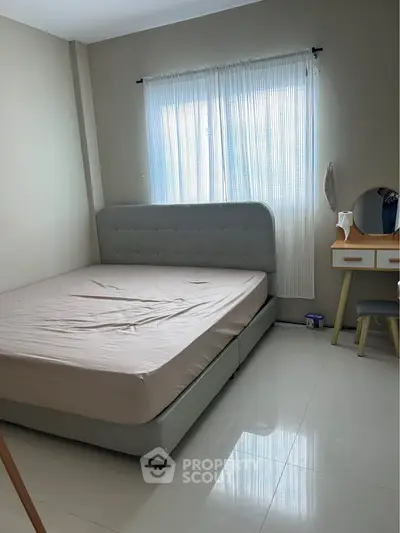 Cozy bedroom with stylish bed and natural light through sheer curtains, perfect for relaxation.