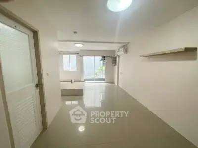Spacious unfurnished living room with large window and modern lighting.