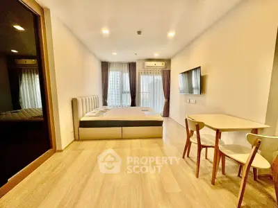 Modern bedroom with sleek design, featuring a cozy bed, stylish table, and large TV, perfect for urban living.