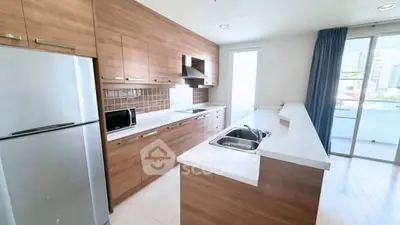 Modern kitchen with wooden cabinets, stainless steel appliances, and balcony access in a bright apartment.