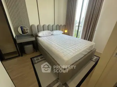 Modern bedroom with stylish decor and large window offering natural light and city view.