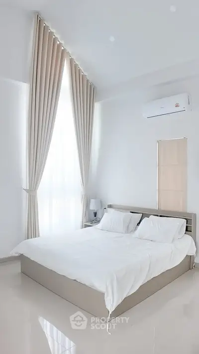 Elegant bedroom with high ceilings and natural light, featuring a cozy bed and modern air conditioning.