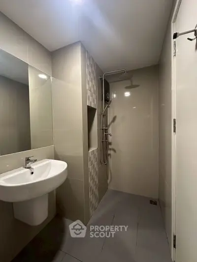 Modern bathroom with sleek shower and sink in contemporary design.