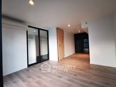 Spacious modern living room with wooden flooring and large glass doors.