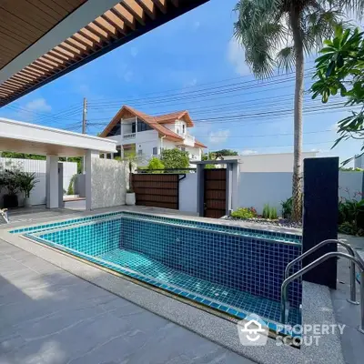 Luxurious outdoor pool area with modern design and lush greenery, perfect for relaxation and entertainment.