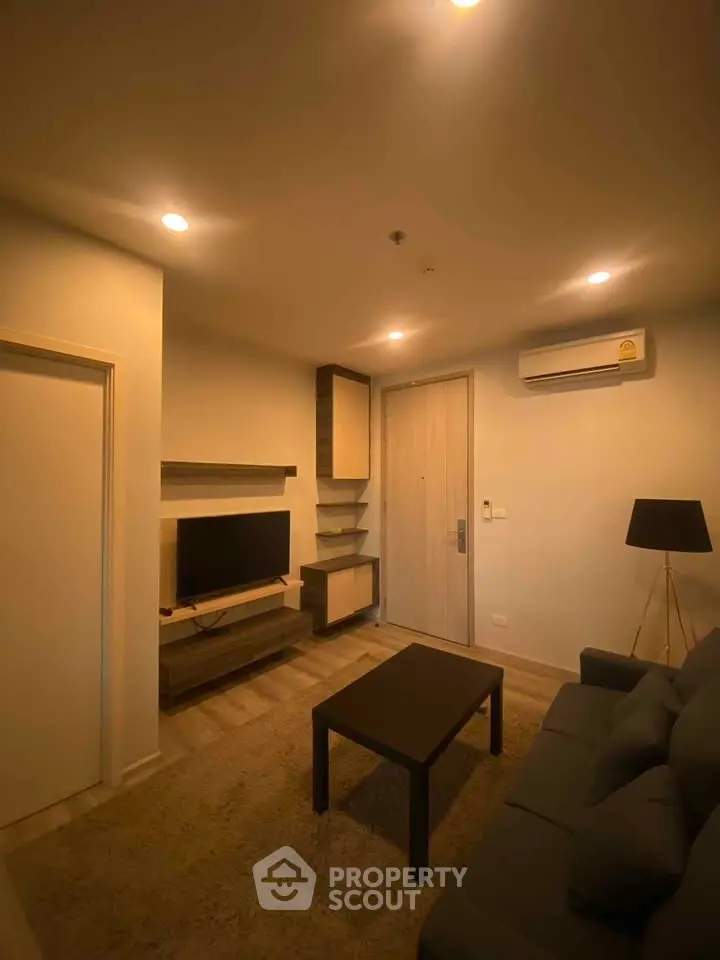 Cozy living room with modern decor, featuring a comfortable sofa, wall-mounted TV, and stylish lighting.