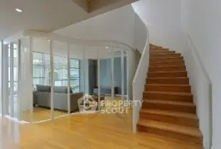 Modern interior with curved glass walls and wooden staircase in a stylish living space.