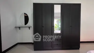 Spacious bedroom with elegant black wardrobe and round mirror