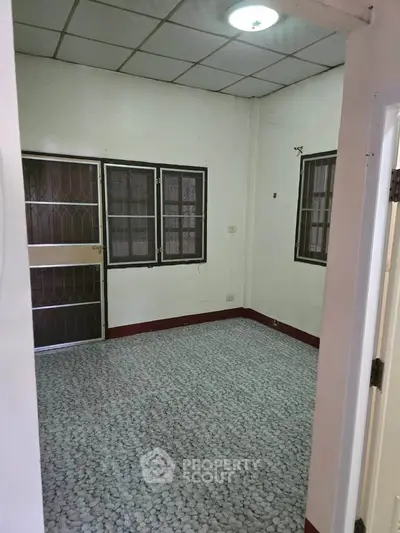 Spacious empty room with tiled floor and barred windows, ready for customization.