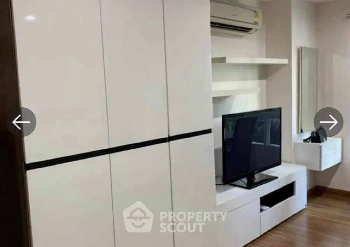 Modern living room with sleek white furniture and wall-mounted TV unit.