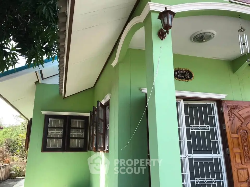 Charming green exterior of a cozy home with decorative lighting and secure entrance.