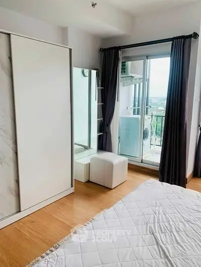 Modern bedroom with balcony view, featuring sleek wardrobe and cozy decor.