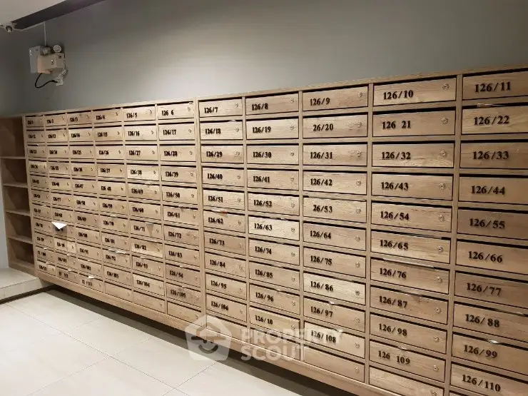 Modern apartment building mailboxes with wooden finish and numbered slots.