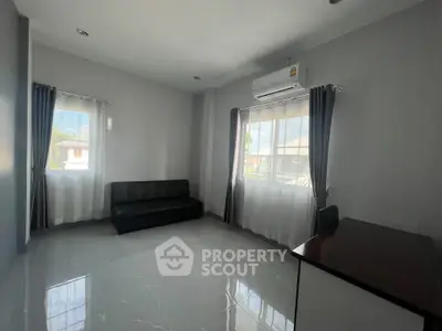 Spacious living room with modern sofa and large windows in a bright, airy home.