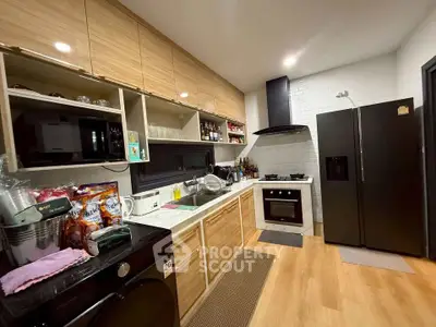 Modern kitchen with wooden cabinets, black fridge, and built-in oven