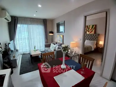 Stylish open-plan living room with dining area and cozy bedroom in modern apartment.