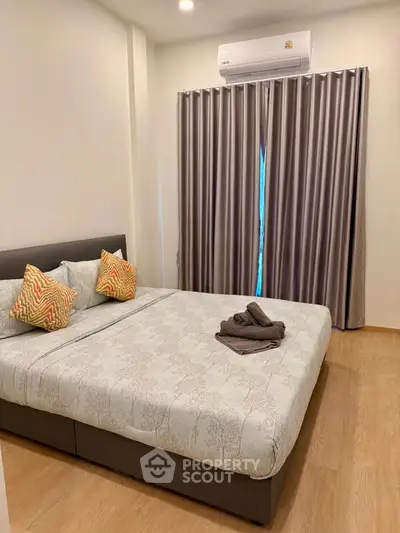 Cozy bedroom with modern decor and air conditioning, featuring elegant curtains and a comfortable bed.