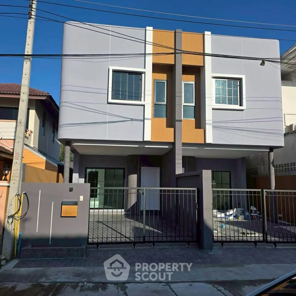 Modern duplex house with sleek facade and gated driveway in a suburban neighborhood.