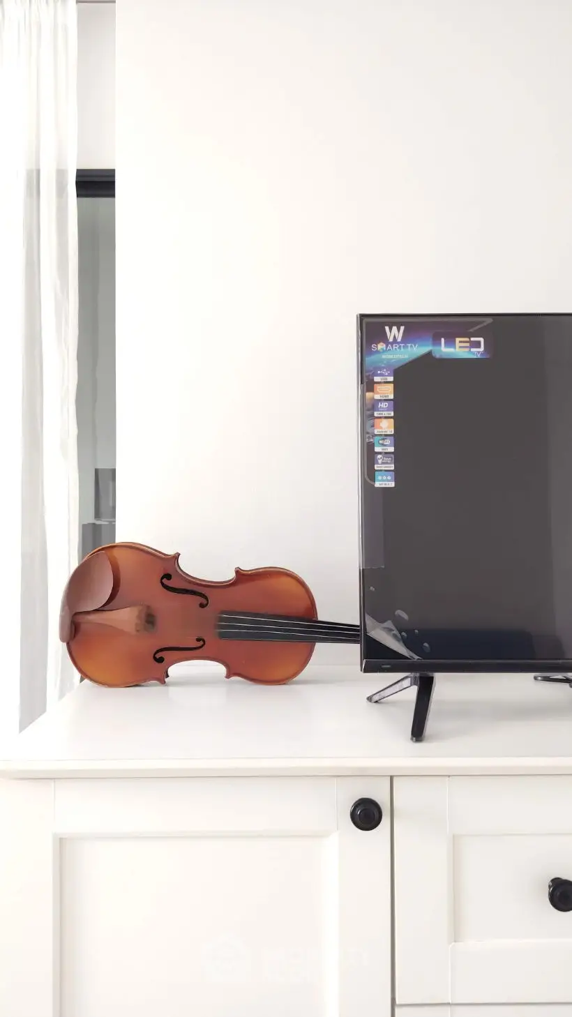Modern living room with sleek TV and elegant violin on white cabinet