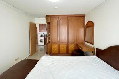 Spacious bedroom with wooden wardrobe and washing machine in view, ideal for modern living.