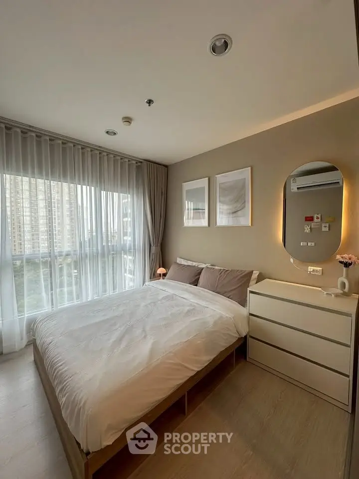 Cozy modern bedroom with large window and stylish decor in urban apartment.