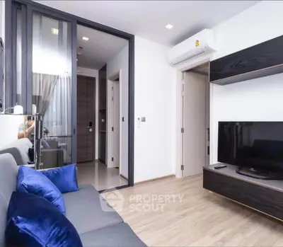 Modern living room with sleek design, featuring a comfortable sofa, wall-mounted TV, and air conditioning.