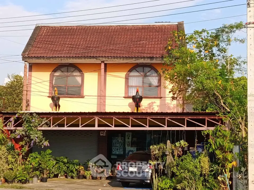 Charming two-story house with unique rooster statues and lush greenery