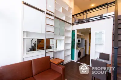 Modern loft apartment with open living space and mezzanine level, featuring sleek furniture and built-in shelves.