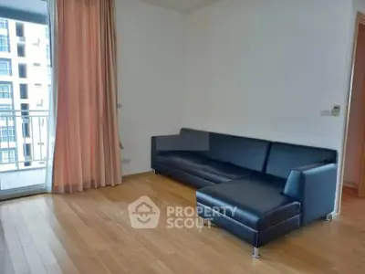 Spacious living room with modern black leather sofa and balcony access