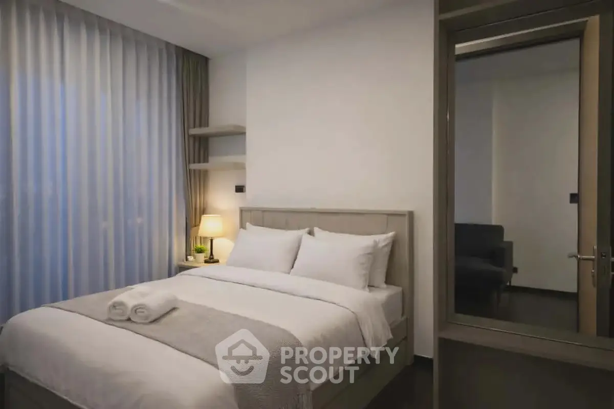Modern bedroom with cozy bed and ambient lighting in a stylish apartment.