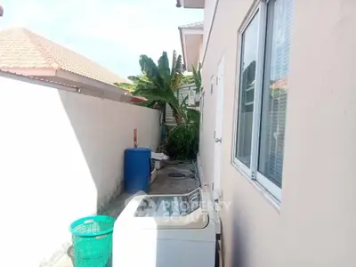 Outdoor laundry area with washing machine and tropical plants