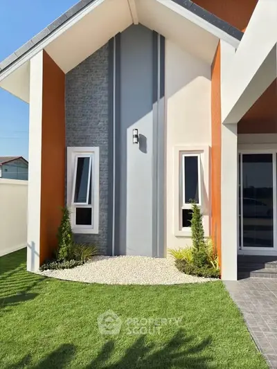 Modern house exterior with unique architectural design and lush green lawn.