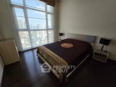 Spacious bedroom with large window offering stunning city views and elegant decor.