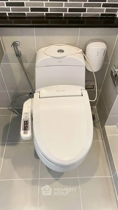 Modern bathroom with high-tech toilet featuring bidet and control panel.