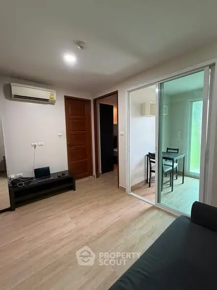 Modern apartment living room with sliding glass doors and wooden flooring.