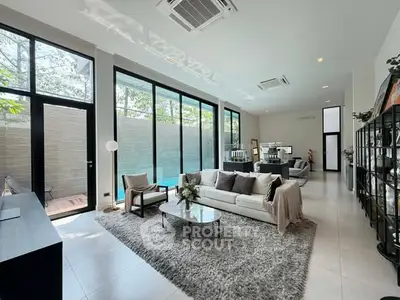 Spacious modern living room with large windows and pool view, featuring elegant decor and ample natural light.
