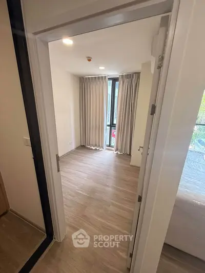 Spacious bedroom with large window and elegant curtains in modern apartment.